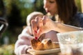 Woman holding a baby as they sit outdoors taking a piece of croissant