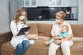 Woman holding baby while doctor writing in clipboard Royalty Free Stock Photo