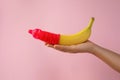 Woman holding banana in condom on pink background, closeup. Safe sex concept Royalty Free Stock Photo