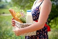 Woman holding a basket with bread, milk and flowers in a summer Royalty Free Stock Photo