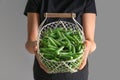 Woman holding basket with fresh green peas on grey background Royalty Free Stock Photo