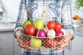 Woman holding basket full of fresh vegetables and fruits in kitchen Royalty Free Stock Photo