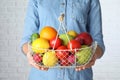 Woman holding basket with ripe fruits and vegetables near white brick wall Royalty Free Stock Photo