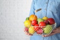 Woman holding basket with ripe fruits and vegetables near white brick wall. Space for text Royalty Free Stock Photo