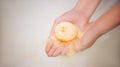 Woman holding bath bomb over water with foam, above view. Space for text Royalty Free Stock Photo