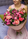 Woman holding a beautiful bouquet of large purple roses in a kraft paper Royalty Free Stock Photo