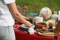 Woman holding beautiful bowls near table with different items on garage sale, closeup