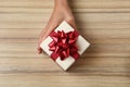 Woman holding beautiful gift box over wooden table Royalty Free Stock Photo