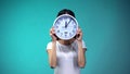 Woman holding big clock before her face, time management and routine, deadline Royalty Free Stock Photo