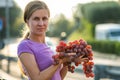 A woman holding big cluster of red juicy grapes in her hand