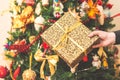 Woman holding a big gift box against amazing christmas tree background. Toned and selective focus Royalty Free Stock Photo