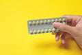 Woman holding birth control pills on yellow background, closeup Royalty Free Stock Photo