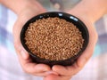 A woman holding a black bowl with buckwheat inside it in her hands