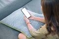 A woman holding black mobile phone with blank white desktop screen while sitting in living room with feeling