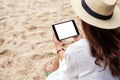 A woman holding a black tablet pc with blank desktop screen while sitting on a beach chair Royalty Free Stock Photo