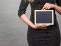 Woman holding blank black board on stomach