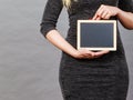 Woman holding blank black board on stomach