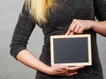 Woman holding blank black board on stomach