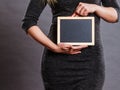 Woman holding blank black board on stomach