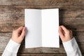 Woman holding blank brochure mock up on wooden table