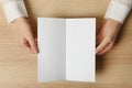 Woman holding blank brochure mock up on wooden table