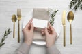 Woman holding blank card near stylish setting at white wooden table, top view. Space for text Royalty Free Stock Photo