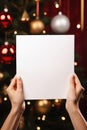 Woman holding blank sheet of paper in front of Christmas tree, closeup Royalty Free Stock Photo