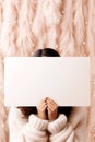 A woman holding a blank sign in front of her face. Peach Fuzz colors, cozy atmosphere. Peach Fuzz color of the year 2024 Royalty Free Stock Photo