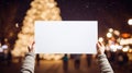 Woman holding a blank white paper in front of a Christmas tree Royalty Free Stock Photo