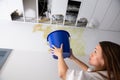 Woman Holding A Blue Bucket Under The Leak Ceiling Royalty Free Stock Photo