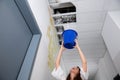Woman Holding A Blue Bucket Under The Leak Ceiling Royalty Free Stock Photo
