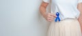 Woman holding Blue ribbon with having Abdomen pain. March Colorectal Cancer Awareness month, Colonic disease, Large Intestine,