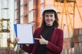 Woman holding blueprints, clipboard. Smiling architect in helmet at building Royalty Free Stock Photo