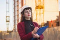 Woman holding blueprints, clipboard. Smiling architect in helmet at building Royalty Free Stock Photo