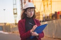 Woman holding blueprints, clipboard. Smiling architect in helmet at building Royalty Free Stock Photo