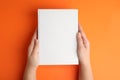 Woman holding book with blank cover on orange background, top view Royalty Free Stock Photo