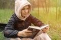 The woman is holding a book in her hands. Reading in the park, in the forest. Rest, training, relaxation concept