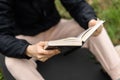 The woman is holding a book in her hands. Reading in the park, in the forest. Rest, training, relaxation concept