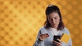 Woman holding books, purchasing more with phone, studio background