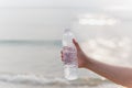 Woman holding bottle mineral water in her hand on the beach. Royalty Free Stock Photo