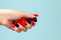 Woman holding bottle of nail polish. Art Manicure. Modern style red black Nail Polish with triangle. Stylish Colorful stiletto