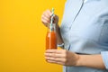 Woman holding bottle of tasty carrot juice on color background, closeup Royalty Free Stock Photo