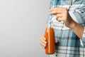 Woman holding bottle of tasty carrot juice on grey background, closeup. Space for Royalty Free Stock Photo