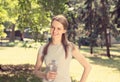 Woman holding bottle of water in hands smiling looking at you camera isolated green trees park background sunny summer weather Royalty Free Stock Photo