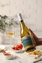 Woman holding bottle of wine over table with different snacks, closeup Royalty Free Stock Photo