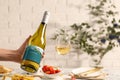 Woman holding bottle of wine over table with different snacks, closeup Royalty Free Stock Photo