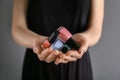 Woman holding bottles of nail polishes on grey background, closeup Royalty Free Stock Photo