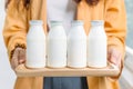 Woman holding bottles of pasteurized yogurt milk in white label color in wooden tray