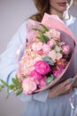 A woman is holding a bouquet of flowers. The florist creates a pink beautiful bouquet of mixed flowers. Peony roses.