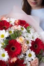 A woman is holding a bouquet of gerbera flowers. The florist creates a red beautiful bouquet of mixed flowers.